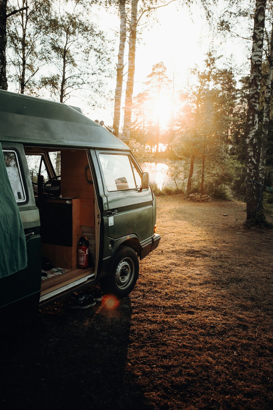 Dunkelgrüner Campervan bei Sonnenuntergang mit offener Tür.